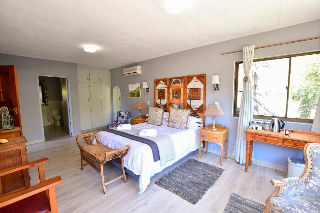 a bedroom with a bed and a desk and a window at Clarens Lantern in Clarens