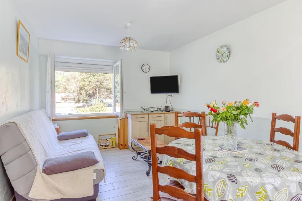 a dining room with a table and chairs and a tv at Le Bas Mont-Dore in La Bourboule