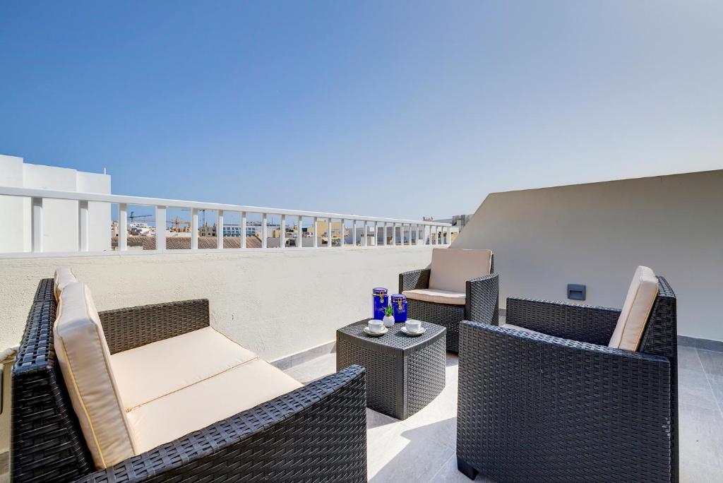 un patio con sillas de mimbre y mesas en un balcón en Chic 2BR Penthouse steps from the Promenade, en Sliema