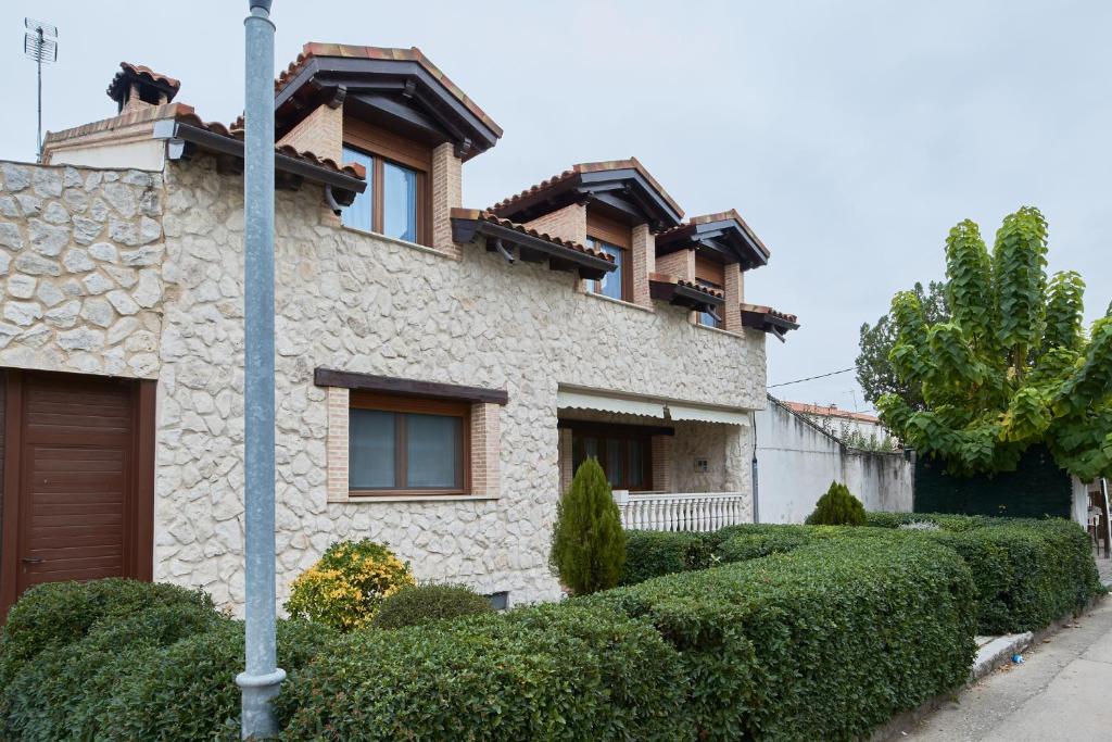 una casa de piedra con arbustos delante de ella en CASA RURAL ENTREVIÑAS, en San Bernardo