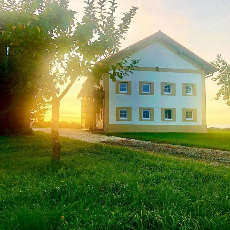 a white house in a field with a tree at Ferienhaus Rabenbrunn in Arnstorf