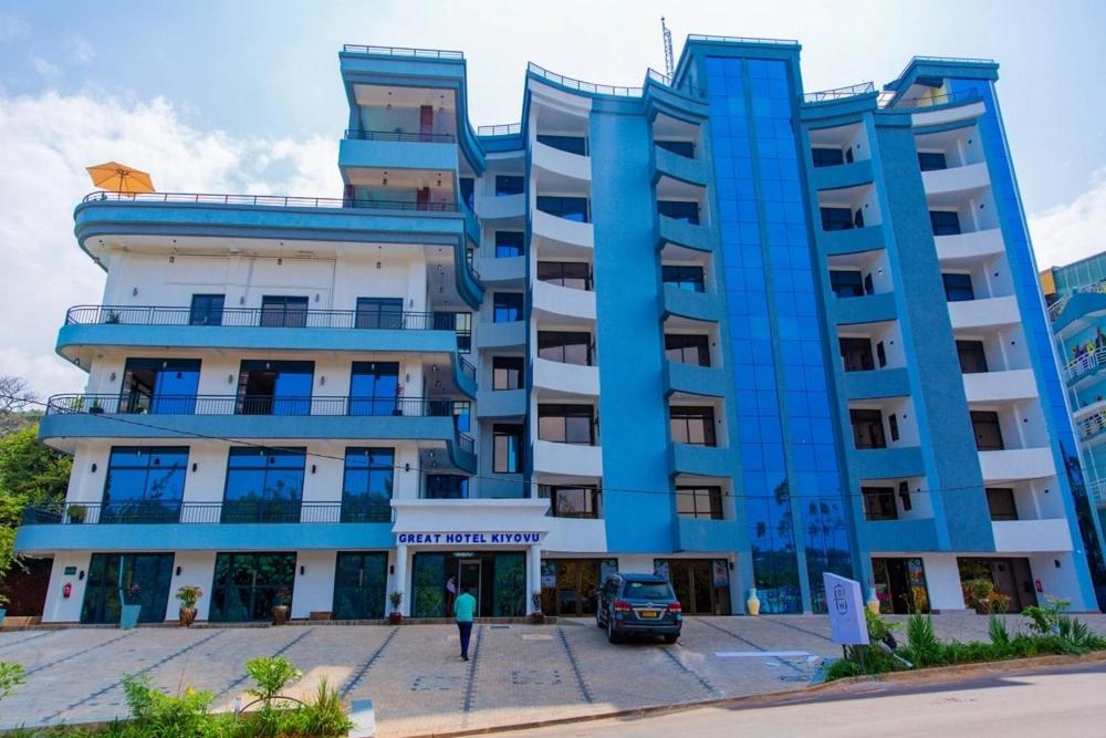 a large blue building with a person walking in front of it at Great Hotel Kiyovu in Kigali