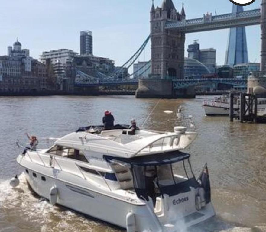 een witte boot in het water voor een brug bij Yacht -Central London St Kats Dock Tower Bridge in Londen