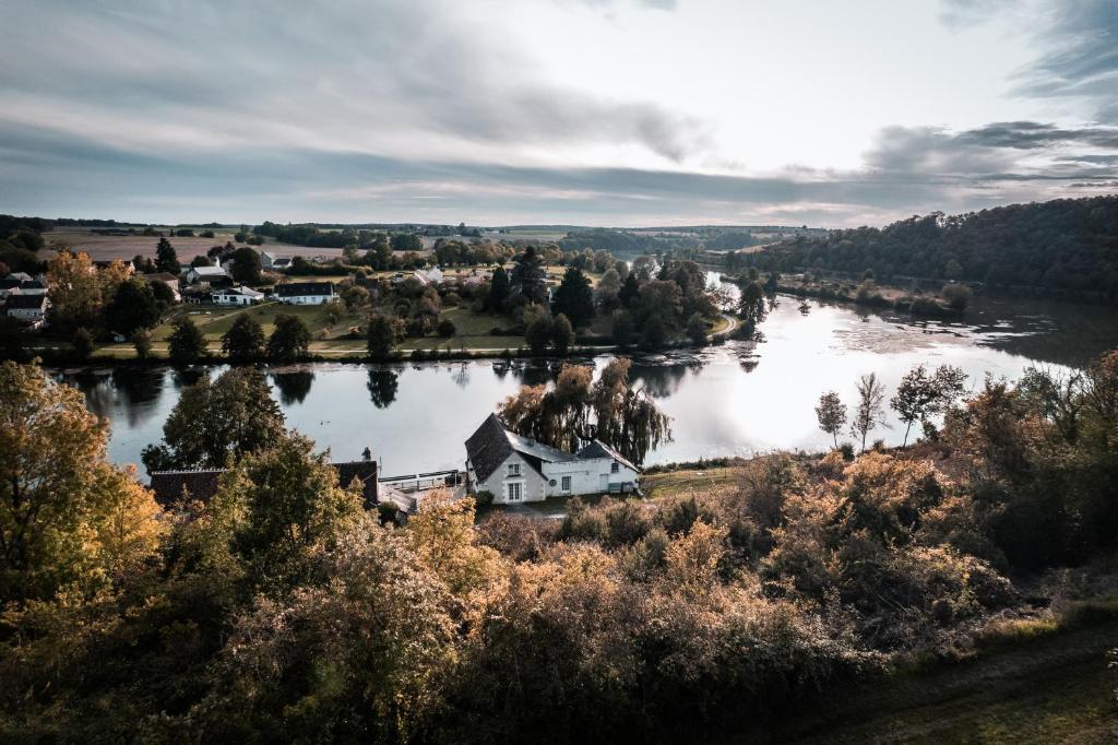 a view of a river with a house and a town at La Maison au Bord du Lac in Chemillé-sur-Indrois