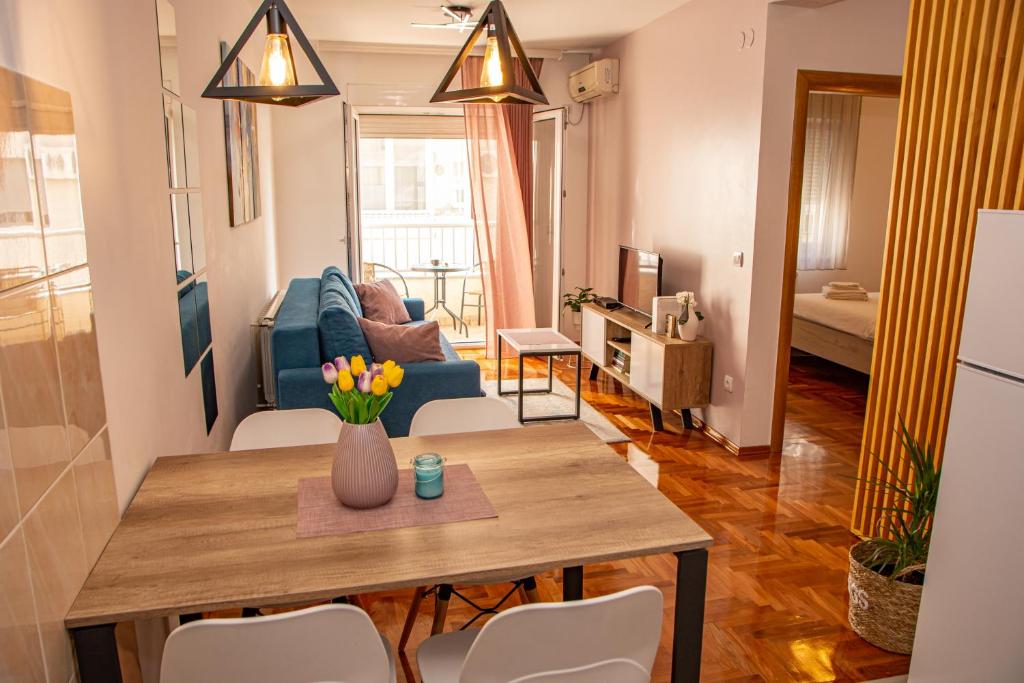 ein Wohnzimmer mit einem Tisch und einem blauen Sofa in der Unterkunft Harizma apartmani in Kragujevac