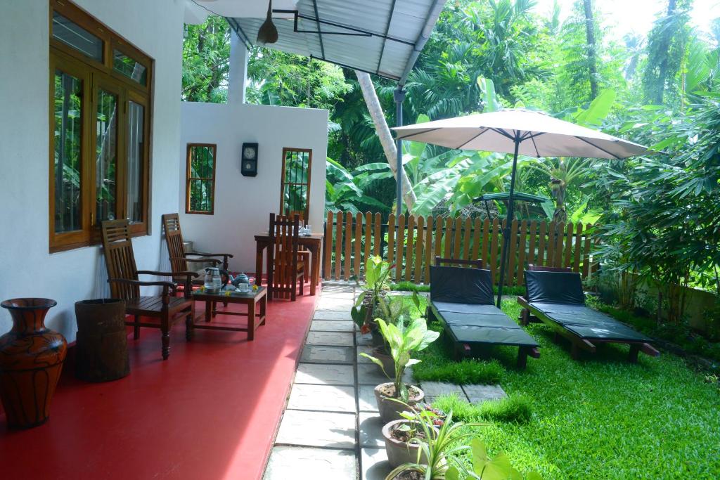 eine Terrasse mit Stühlen und einem Sonnenschirm in einem Haus in der Unterkunft Gold sand Resort in Bentota