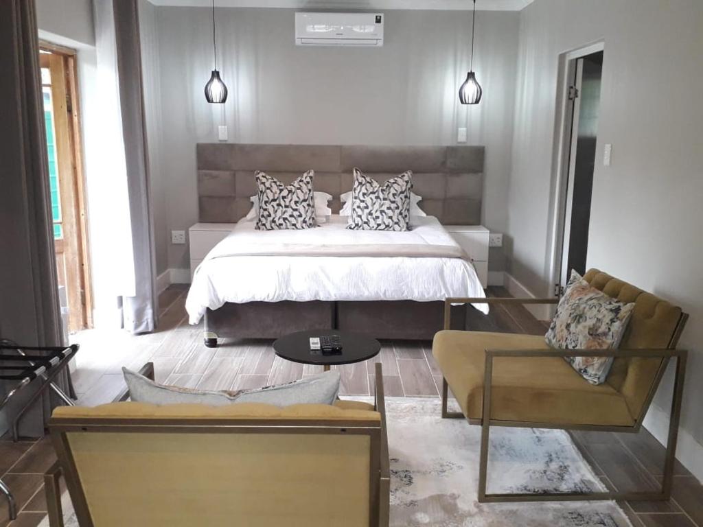 a bedroom with a bed and a couch and a chair at Sani Pass Manor Guest House in Himeville