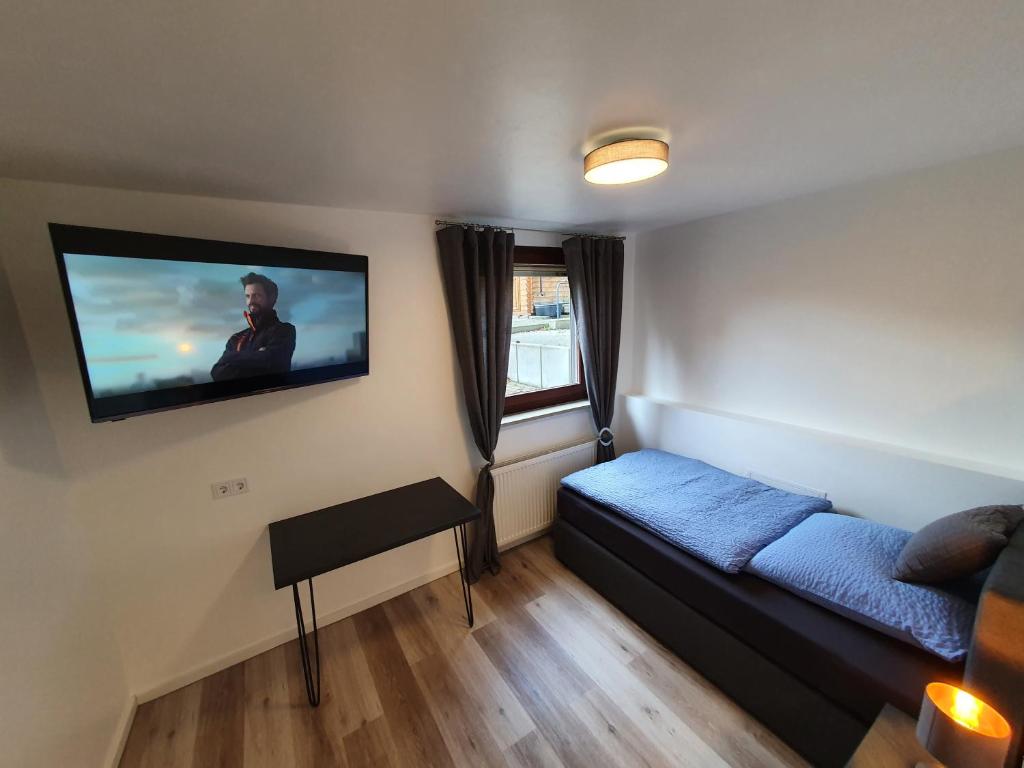 1 dormitorio con 1 cama y TV en la pared en Haus Fasanerie, en Fulda