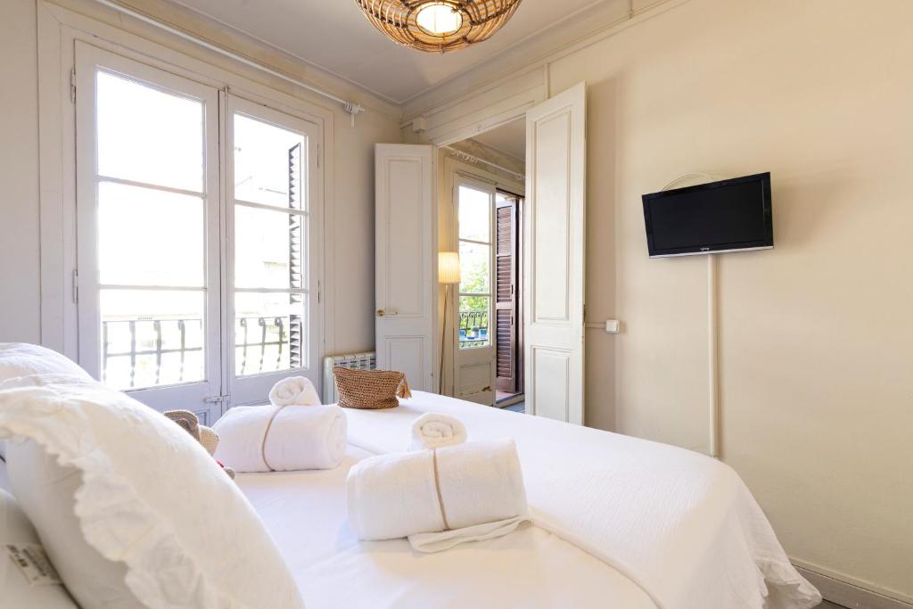 een slaapkamer met een wit bed en een tv aan de muur bij Urban Apartments in Barcelona