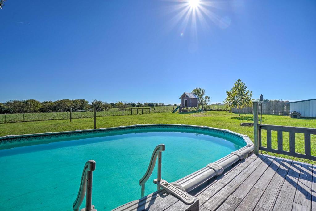 a swimming pool with a wooden deck and a fence at Monett Family Ranch Home with Fireplace and Huge Deck! in Monett