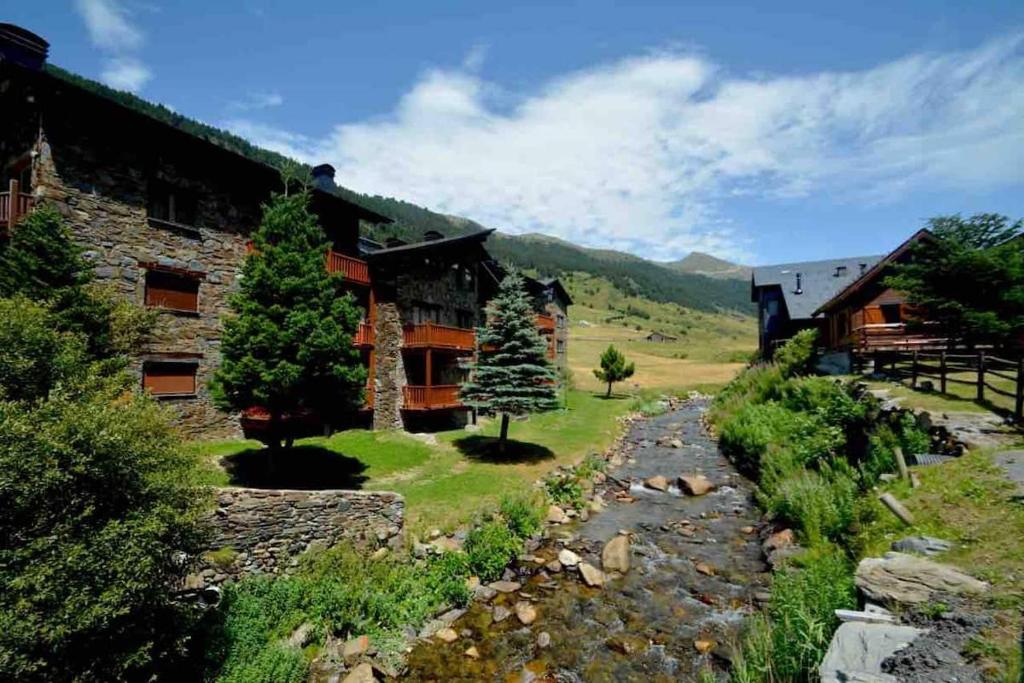 eine Blockhütte mit einem Bach vor einem Haus in der Unterkunft Preciosa Pleta en la Vall d’Incles HUT 7960 in Canillo
