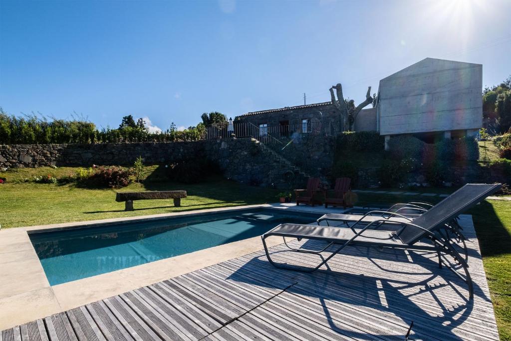 a pool with two chairs and a bench on a deck at Casa do Castanheiro - Nordeste, Açores in Nordeste