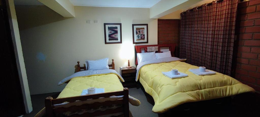 a bedroom with two beds with yellow blankets and a lamp at Mirador Backpackers B&B in Huaraz