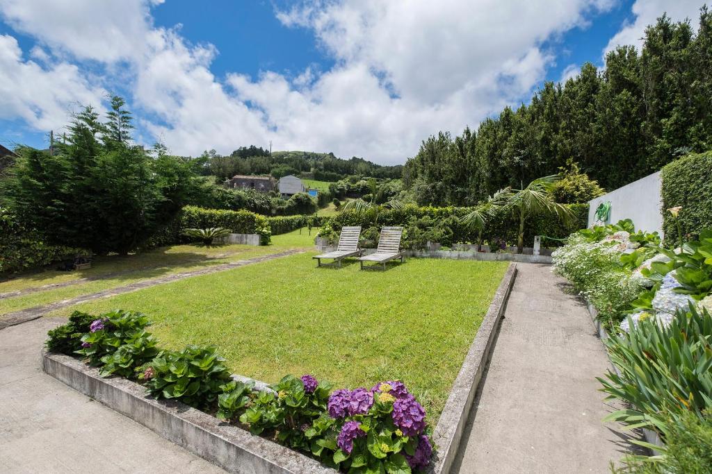 a garden with two park benches and flowers at Casa do Simão in Nordeste
