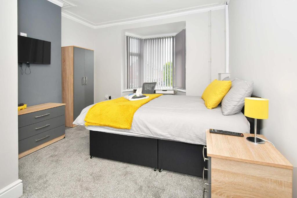 a bedroom with a large bed with a yellow blanket at Townhouse @ Bucknall New Road Stoke in Hanley