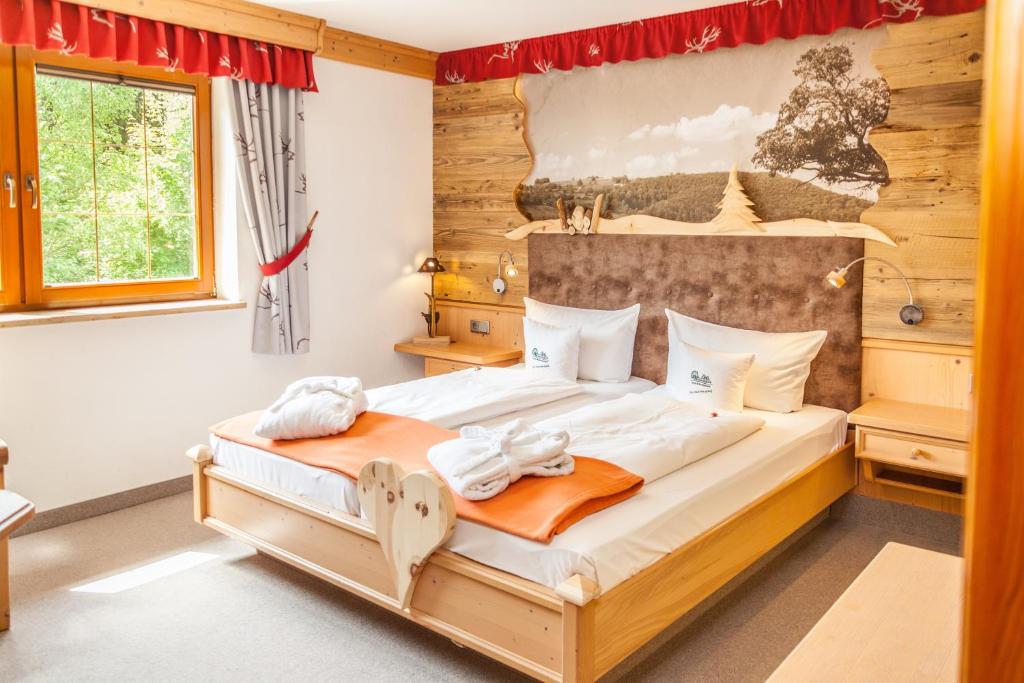 een slaapkamer met een groot bed met een houten hoofdeinde bij Hotel und Restaurant Köhlerhütte - Fürstenbrunn in Beierfeld