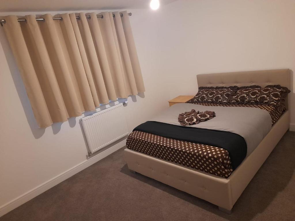 a bed in a room with a window with curtains at Beautiful Double Bedroom- In a modern 2 bed shared house in Chigwell