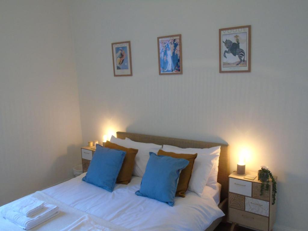 a bedroom with a white bed with blue pillows at Snug - Tearlag Apartment in Helensburgh