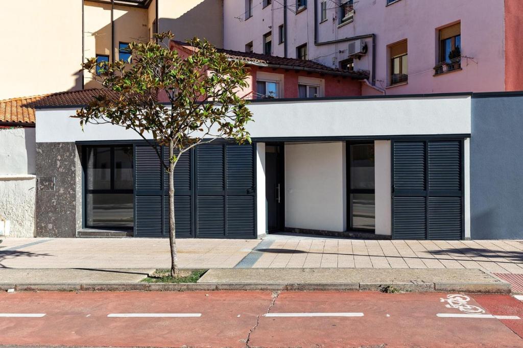 a building with black doors and a tree on a street at A TU VERA VUT-09/298 in Burgos