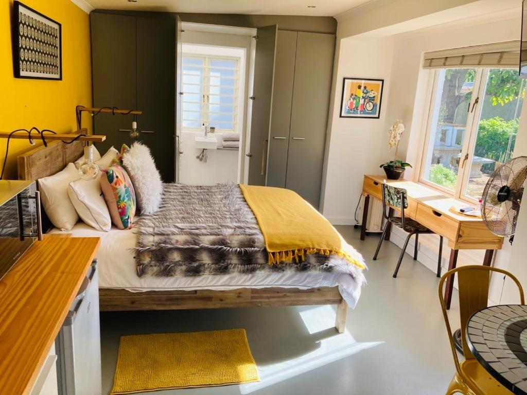 um quarto com uma cama, uma mesa e uma secretária em Modern studio apartment na Cidade do Cabo