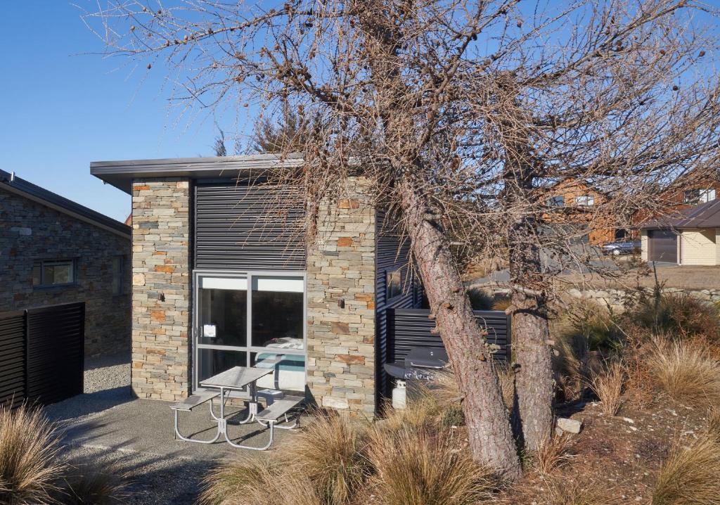 ein Backsteinhaus mit einer Terrasse und einem Baum in der Unterkunft Little Rock in Lake Tekapo