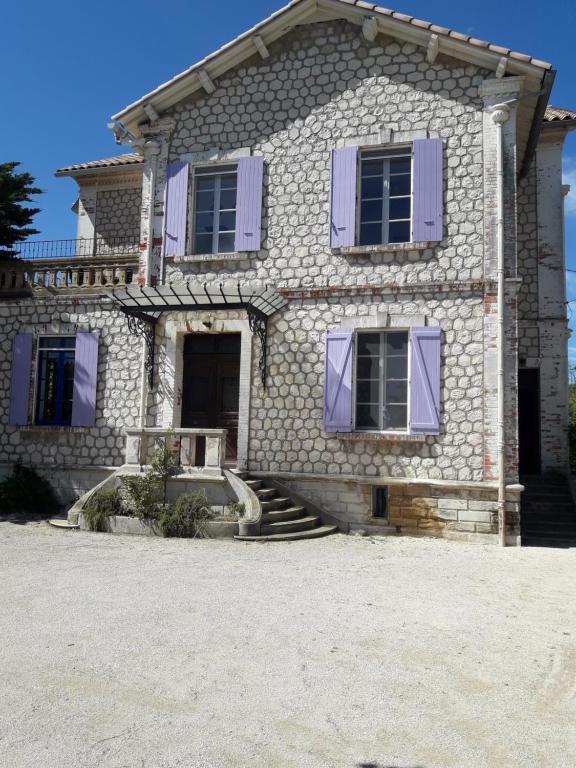 a stone house with purple shutters on it at LA MAISON DU DIRECTEUR DE SALIN DE GIRAUD in Salin-de-Giraud