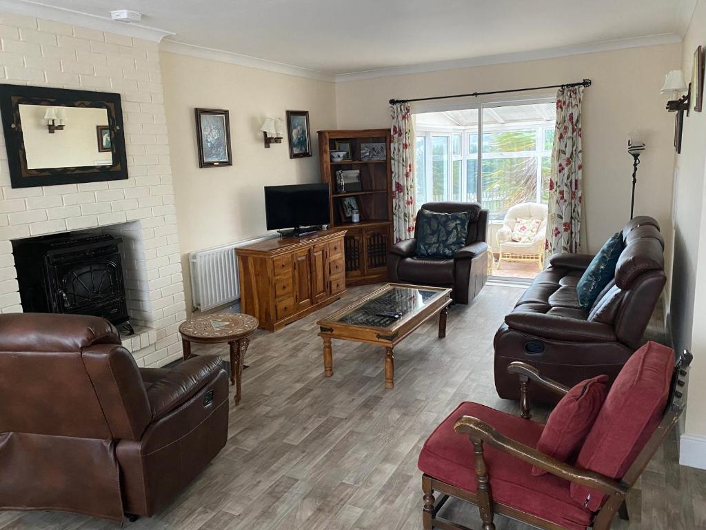 a living room with leather furniture and a fireplace at Cozy seaside home,3 minute walk to village/beach in Lahinch