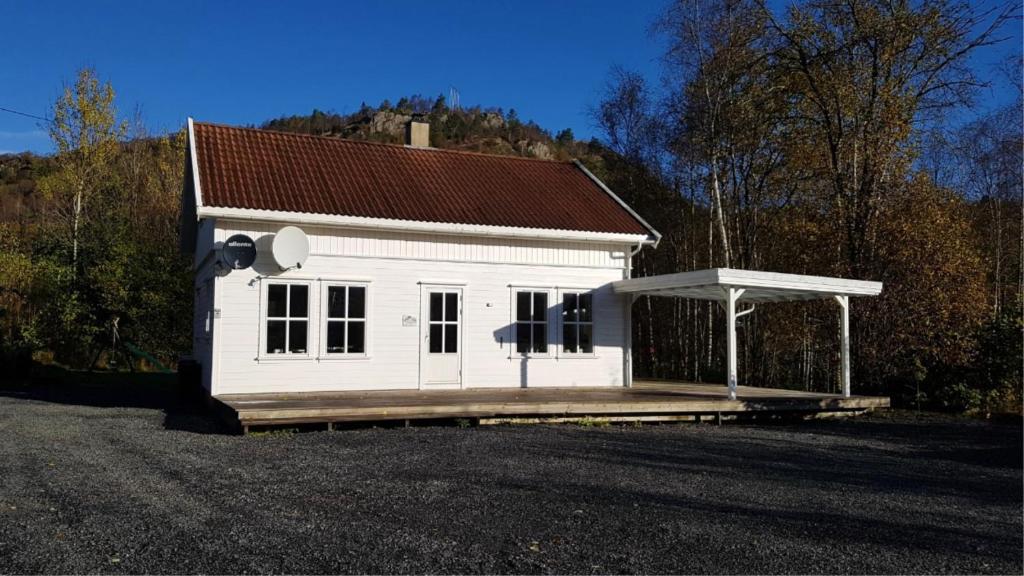 una pequeña casa blanca con un porche en mucho en Slåta - The Dragon-valley cabin, en Lyngdal