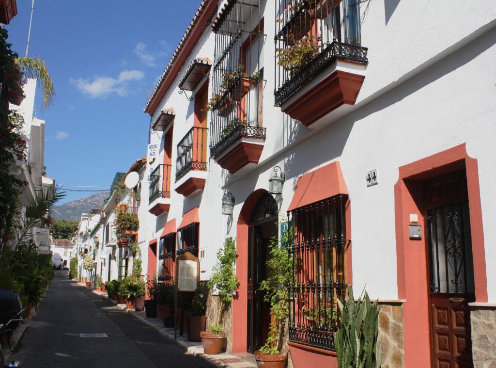 una strada in una città con balconi e piante di Hostal El Gallo a Marbella