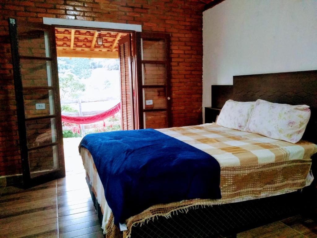 una camera con un letto in una stanza con una porta di Chalés Cachoeira do Cafundó a Bueno Brandão