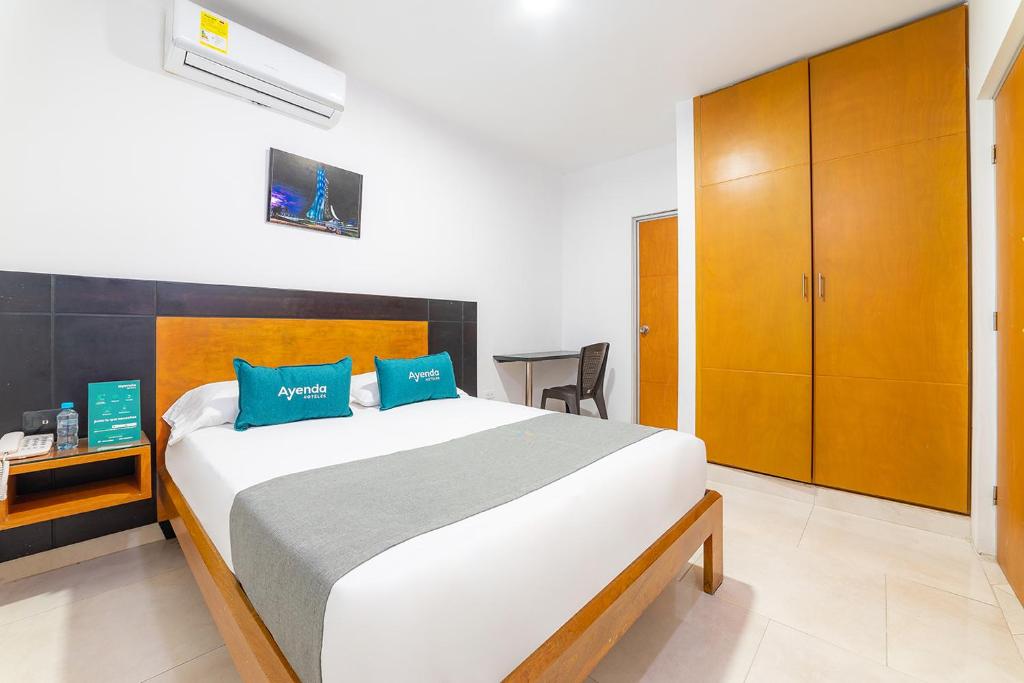 1 dormitorio con 1 cama grande con almohadas azules en Ayenda Zhena, en Cúcuta