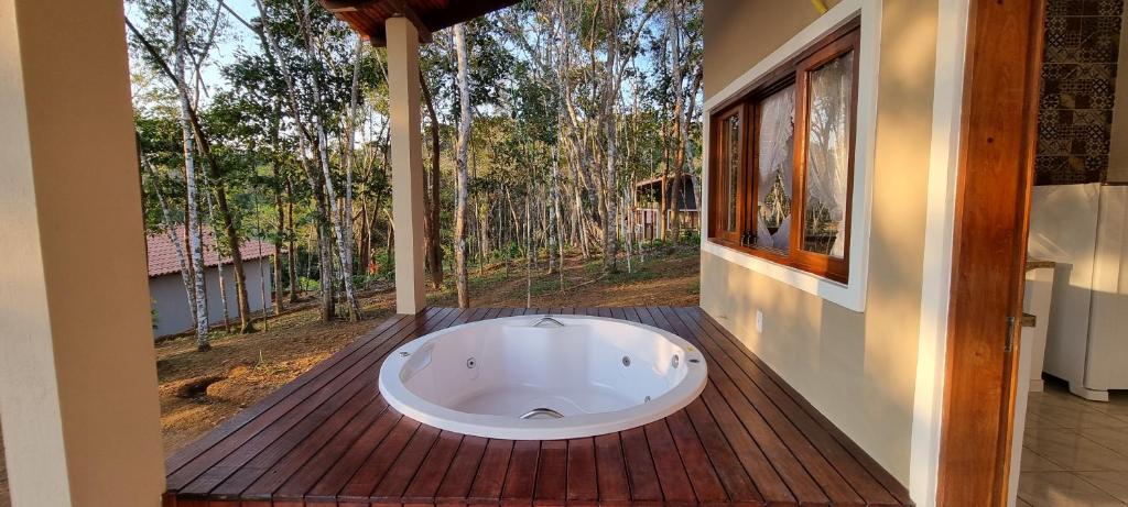 a bath tub sitting on a wooden deck with a window at Chalés Pura Vida in Itacaré