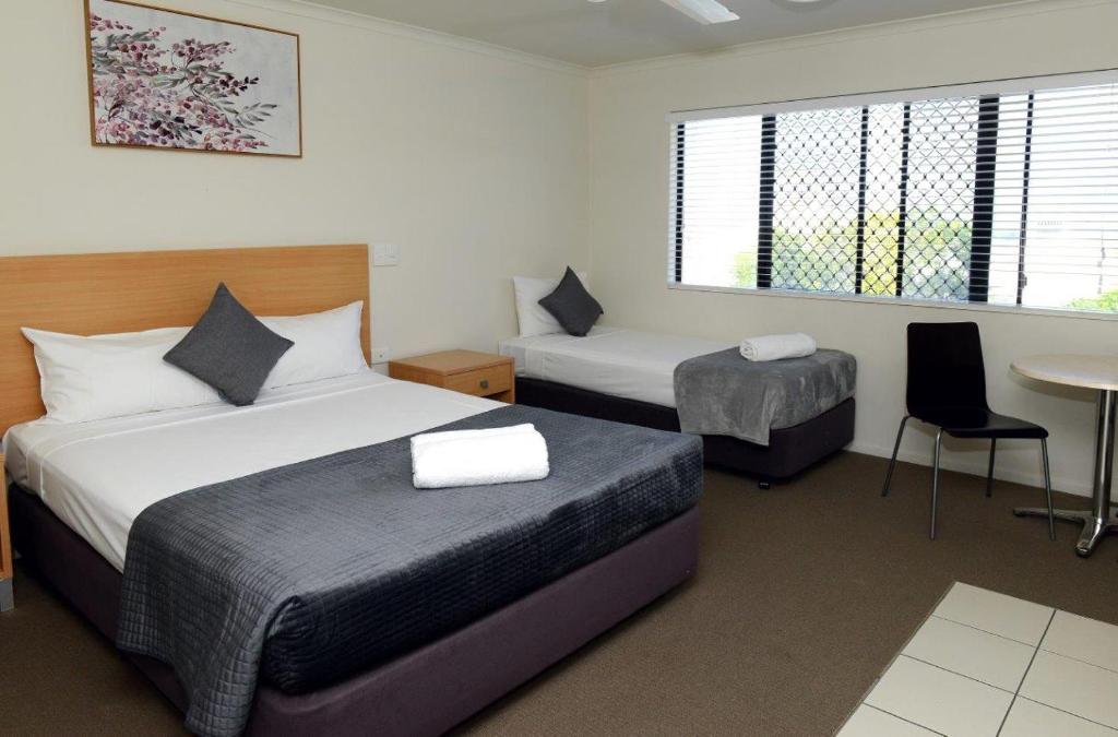 Habitación de hotel con 2 camas, mesa y sillas en Summit Motel en Townsville