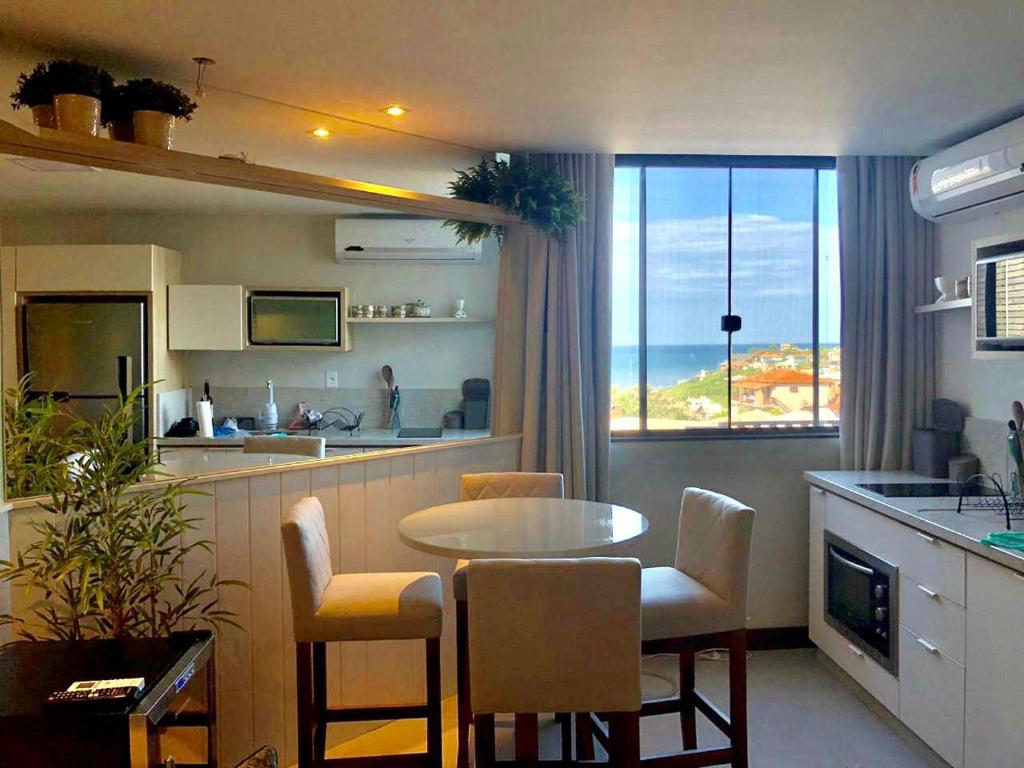 a kitchen and dining room with a table and a view of the ocean at Residence Farol - Loft 213 in Laguna