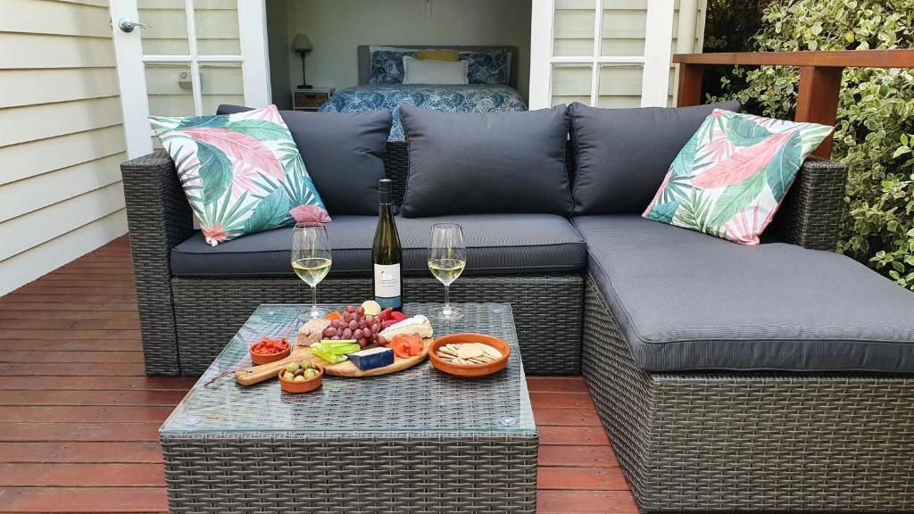 un patio con sofá y una mesa con copas de vino en A Coonawarra Experience, en Penola