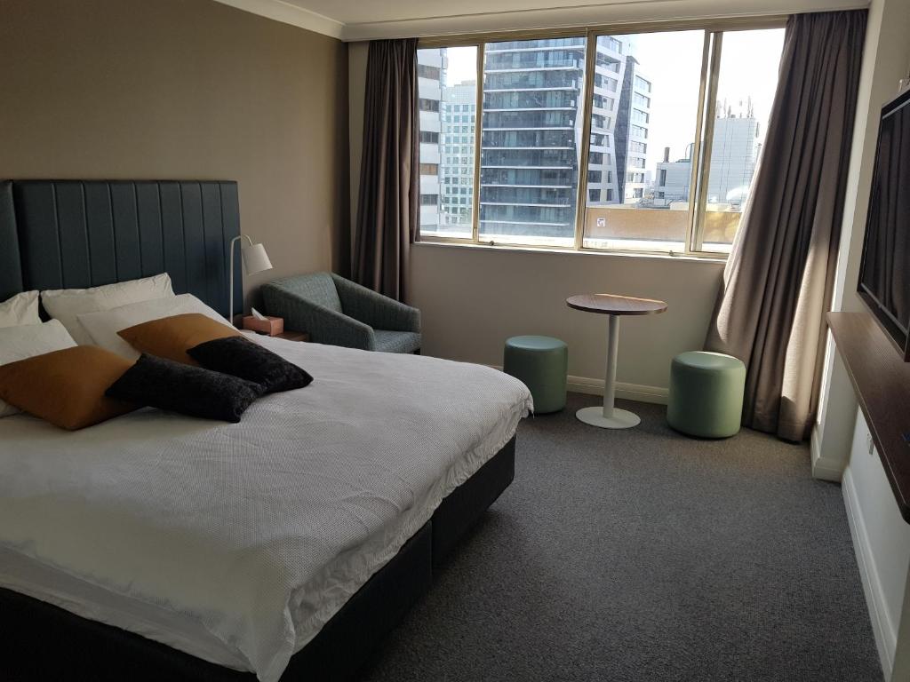 a bedroom with a bed and a chair and a window at Chatswood Hotel Apartment in Sydney