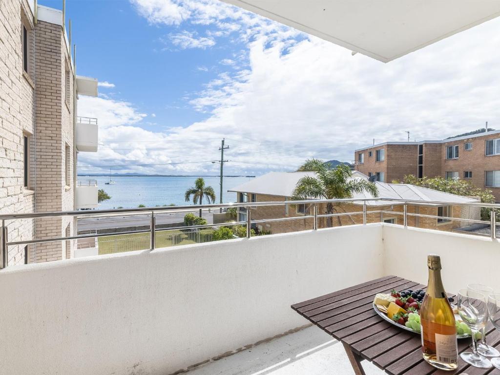 a table with a plate of food and a bottle of wine on a balcony at Del Rae 6 25 Shoal Bay Road in Shoal Bay