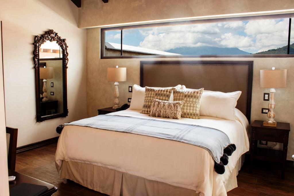 a bedroom with a large bed with a large window at Hotel Boutique Los Pasos & Spa in Antigua Guatemala