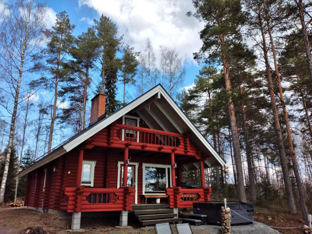 a red cabin in the woods with trees at Temola in Alvajärvi
