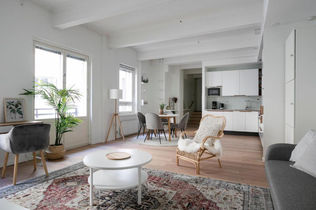 a white living room with a table and chairs at 2ndhomes Loft Apartment with Spa & Balcony by the White Church in Helsinki