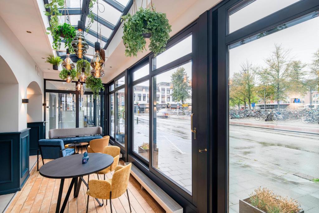 um quarto com uma mesa, cadeiras e janelas em The Rosendale em Roosendaal