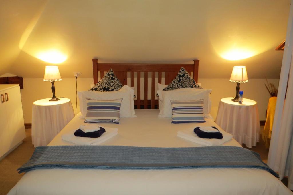 a bedroom with a large white bed with two lamps at The Orange Bowl in Paarl