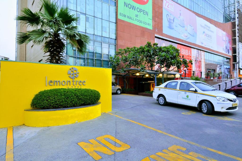 samochód zaparkowany na parkingu przed budynkiem w obiekcie Lemon Tree Hotel, East Delhi Mall, Kaushambi w mieście Ghaziabad