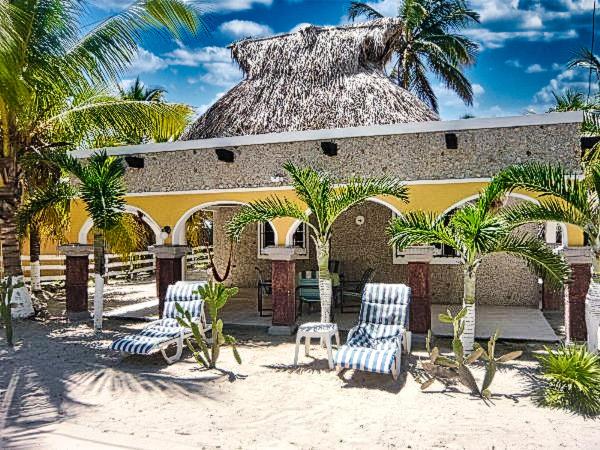 a building with chairs and palm trees in front of it at Hacienda Antigua Villa, 50m from sandy Beach in El Cuyo