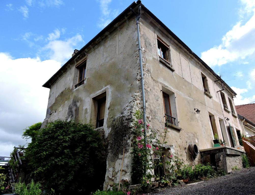 un viejo edificio con flores a un lado. en Gîte Champagne LA PARCELLE, en Connigis