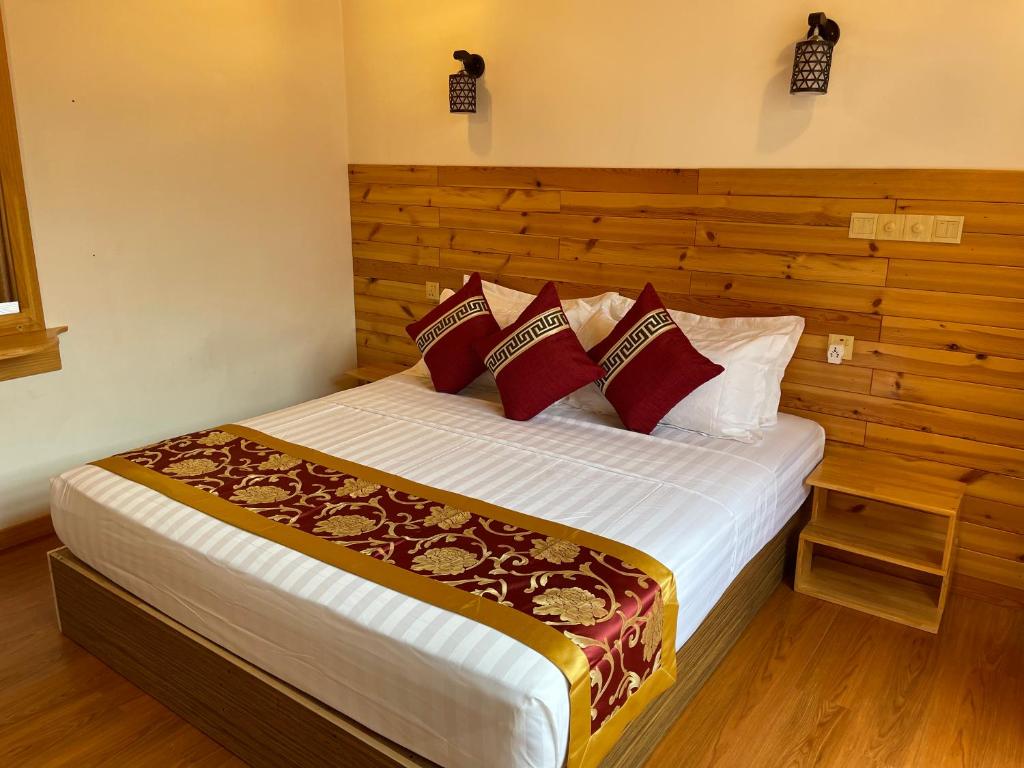 1 dormitorio con 1 cama grande con almohadas rojas en New Breeze Thoddoo Inn, en Thoddoo
