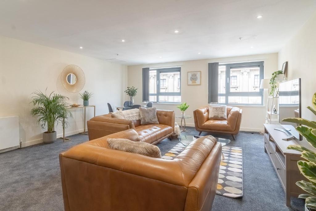 a living room with a leather couch and two chairs at Charming Westend/City centre Apartment in Glasgow