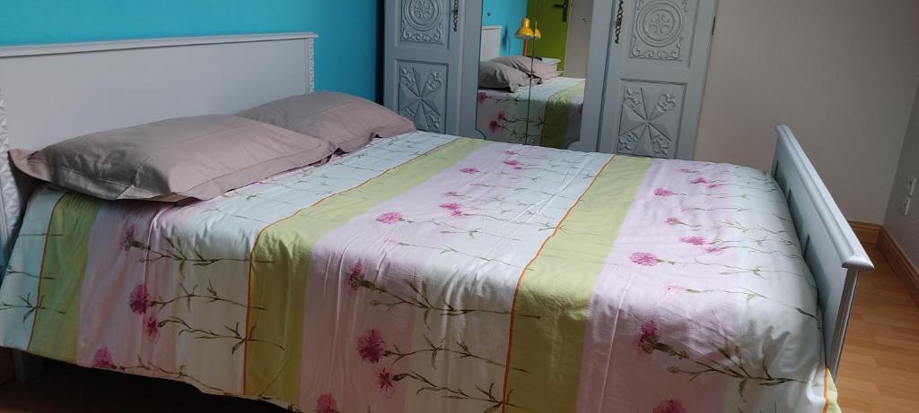 ein Bett mit einer bunten Decke in einem Schlafzimmer in der Unterkunft Chambres au Village in Saint-Mʼhervé