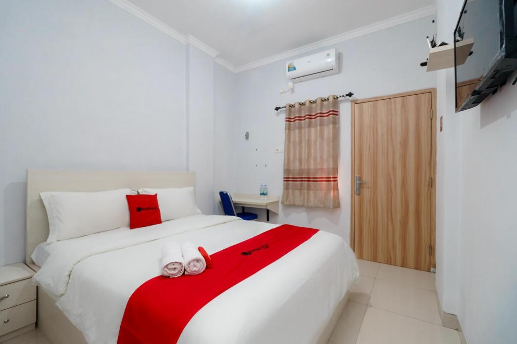 a bedroom with a white bed with a red blanket at RedDoorz near Pantai Barat Pangandaran 2 in Pangandaran