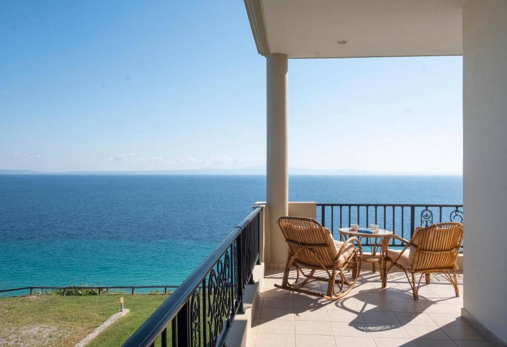 a balcony with chairs and a table and the ocean at Aegean Blue Horizon in Afitos